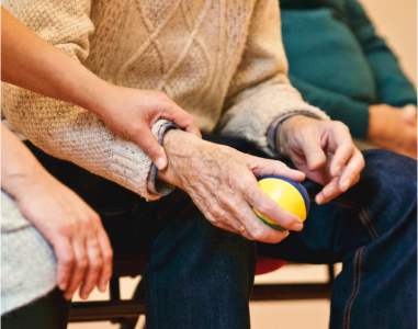 Bild zum Thema Gesundheitsmanagement zeigt ältere Hände, die üben einen kelinen Ball zu halten