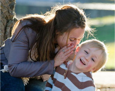 Bild zum Thema Gesundheitsmanagement zeigt eine Frau, die einem kleinen Jungen etwas lachend ins Ohr flüstert